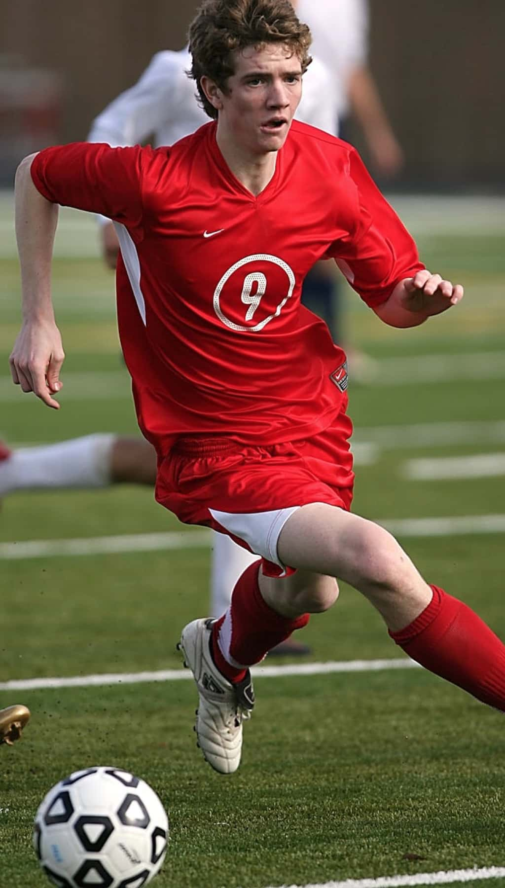 Homme avec un t-shirt rouge jouant au foot.